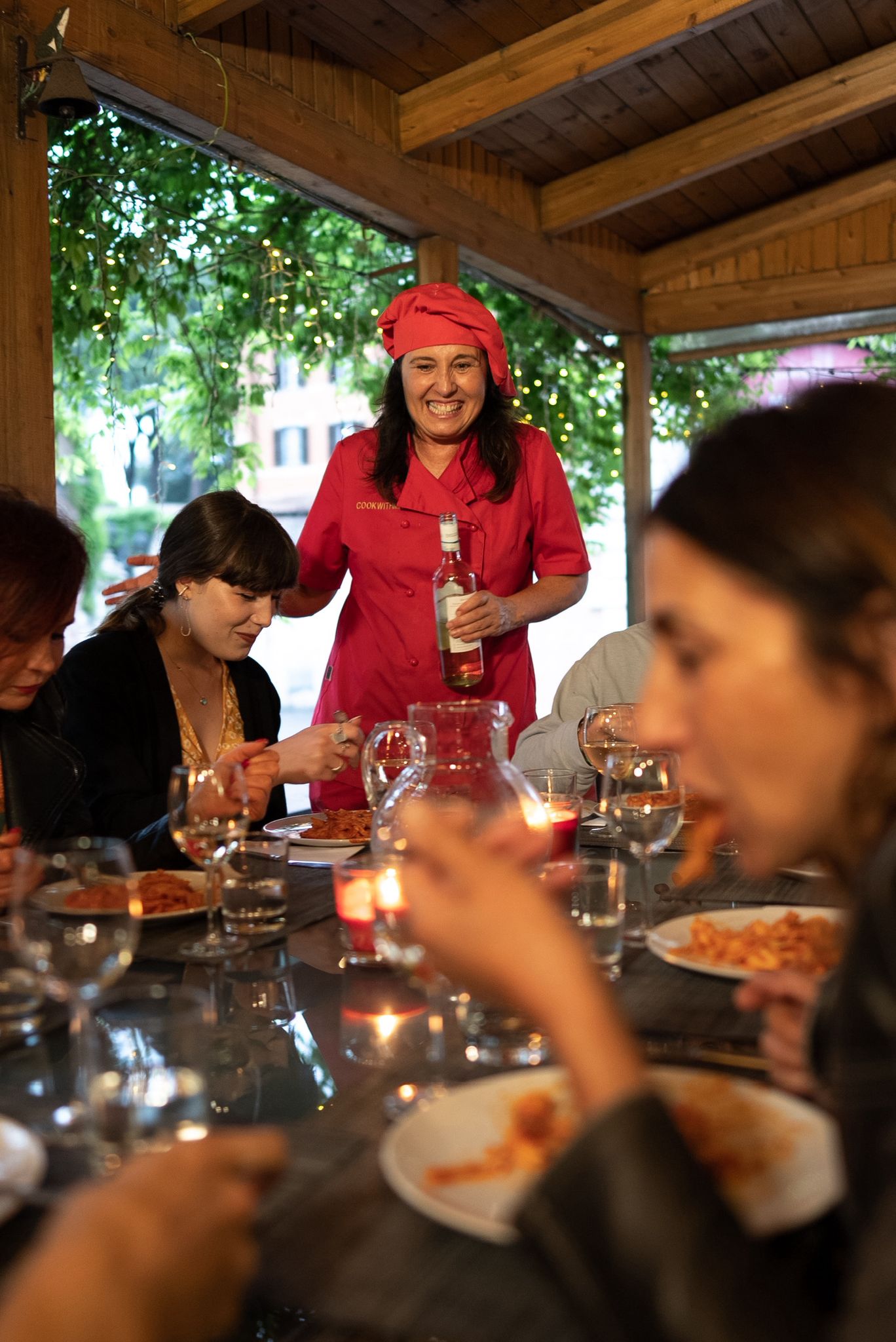 Chef pouring wine for guests seated at a candlelit table