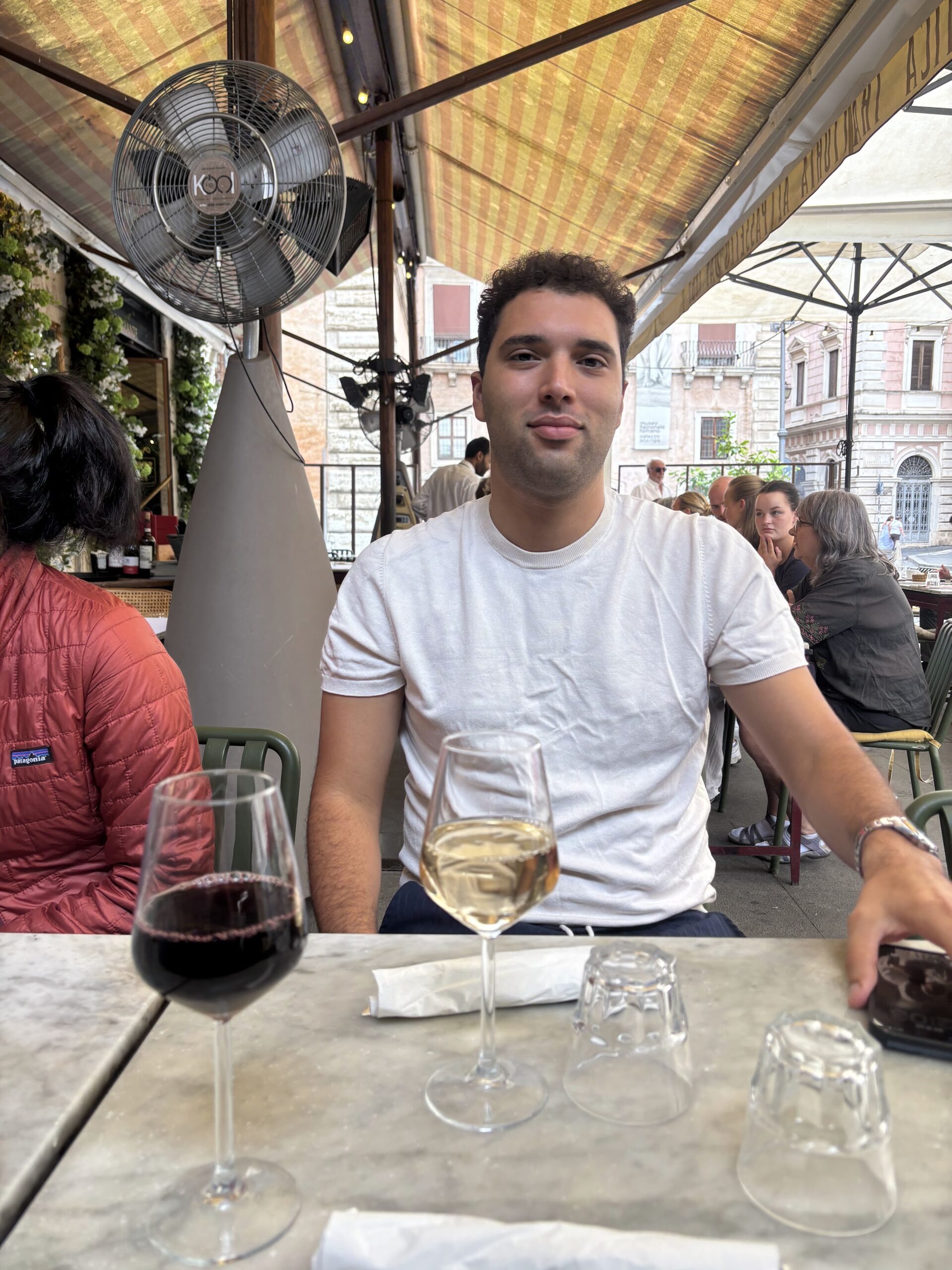 A guest with a glass of red and white wine at a Roman restaurant table