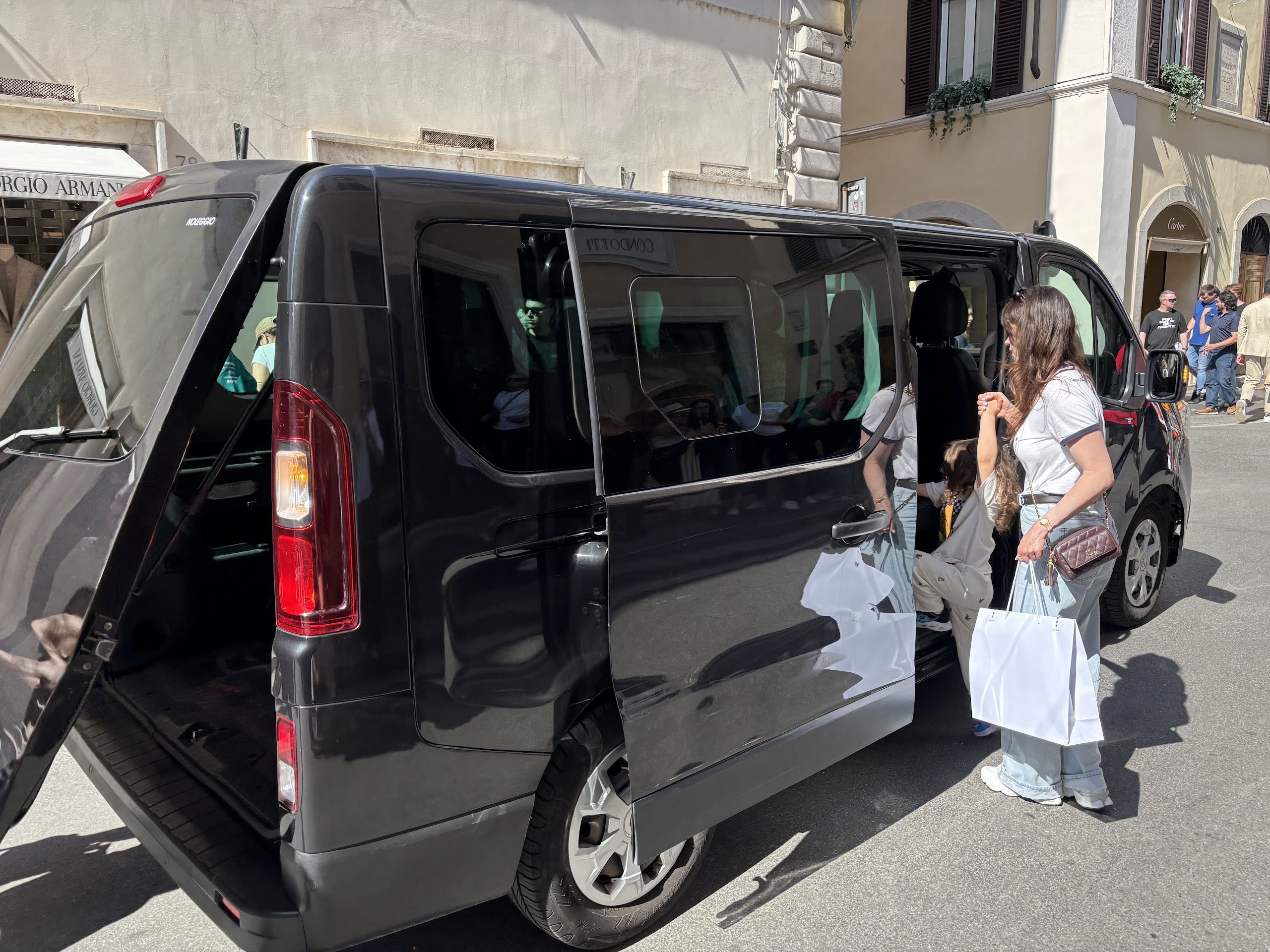 The driver loading shopping bags into the private van on Via dei Condotti
