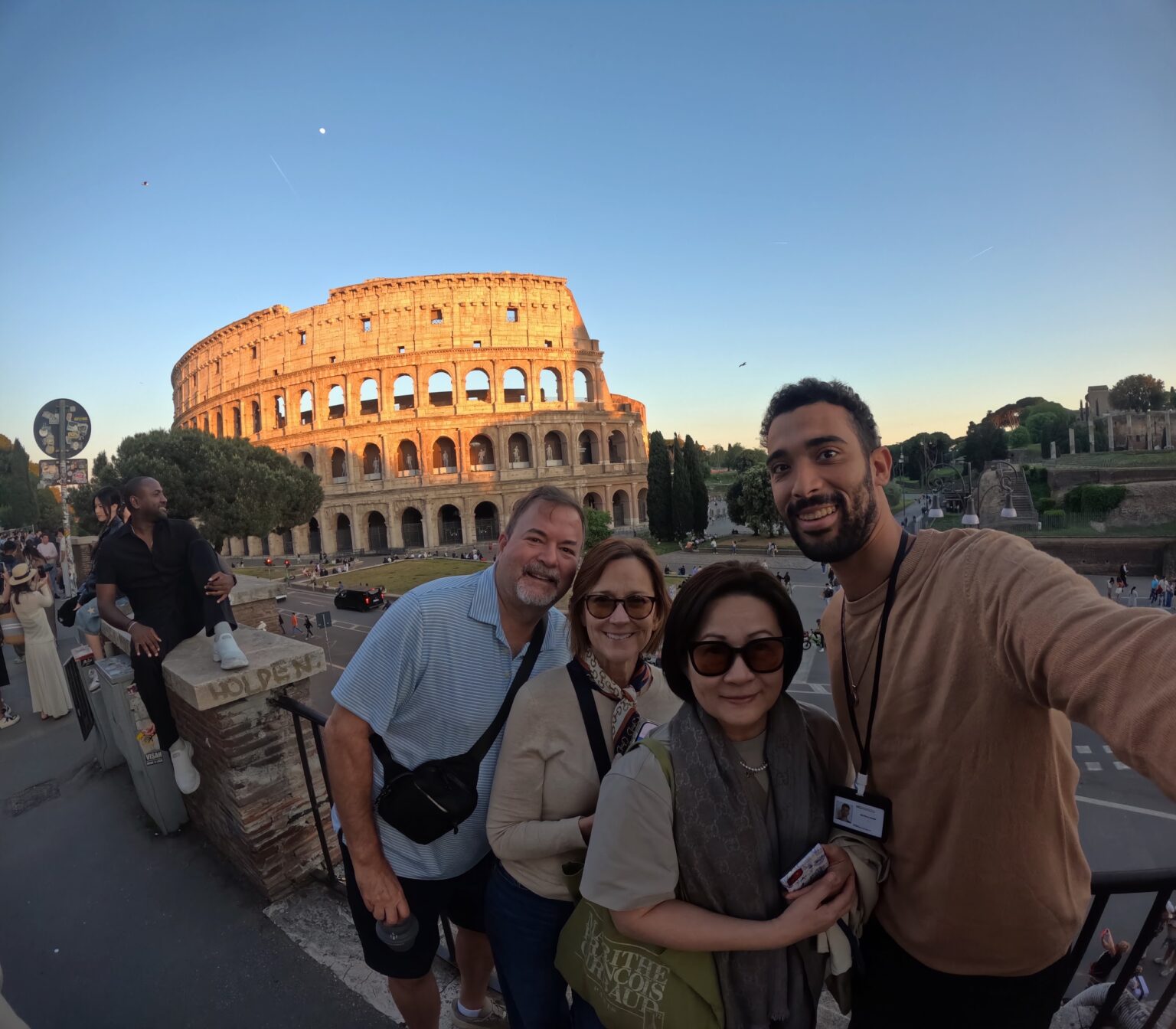 A guide and guests taking a group photo at the Colosseum at sunset