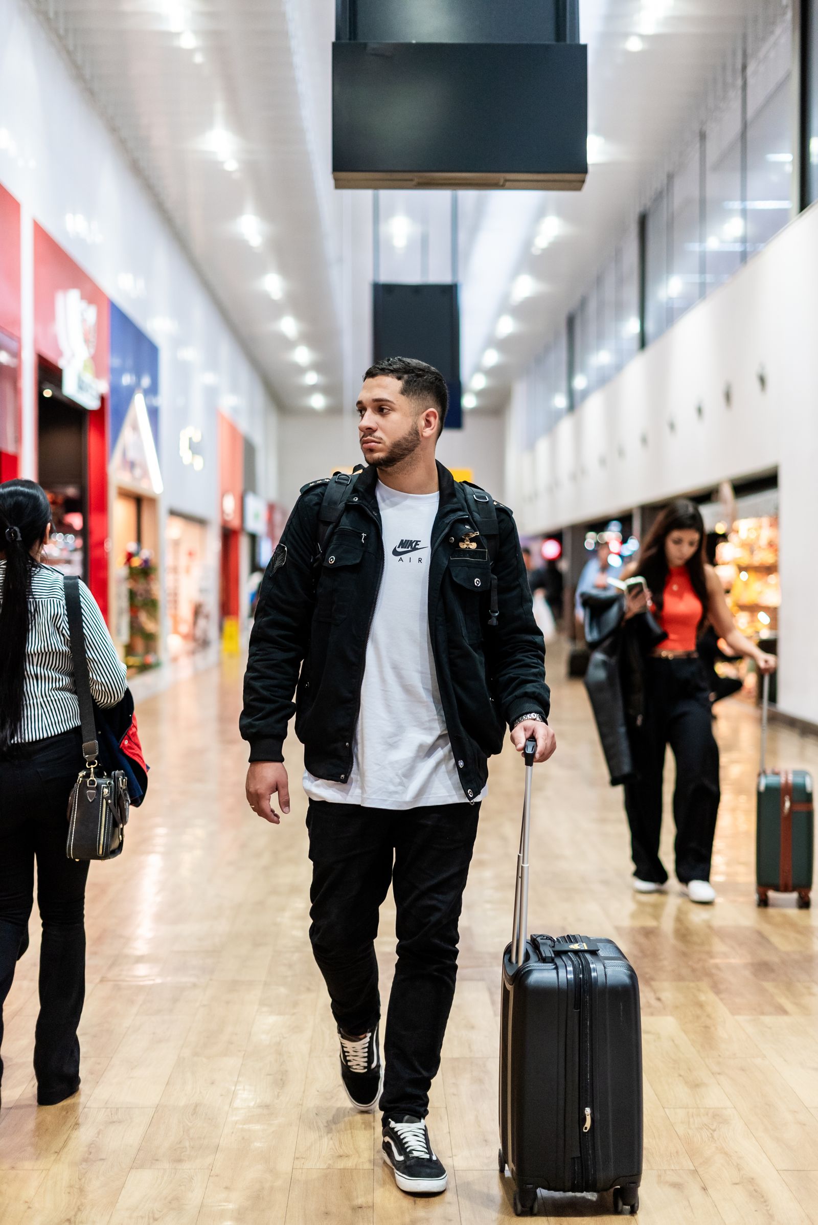 A traveller walking through an airport terminal with a suitcase