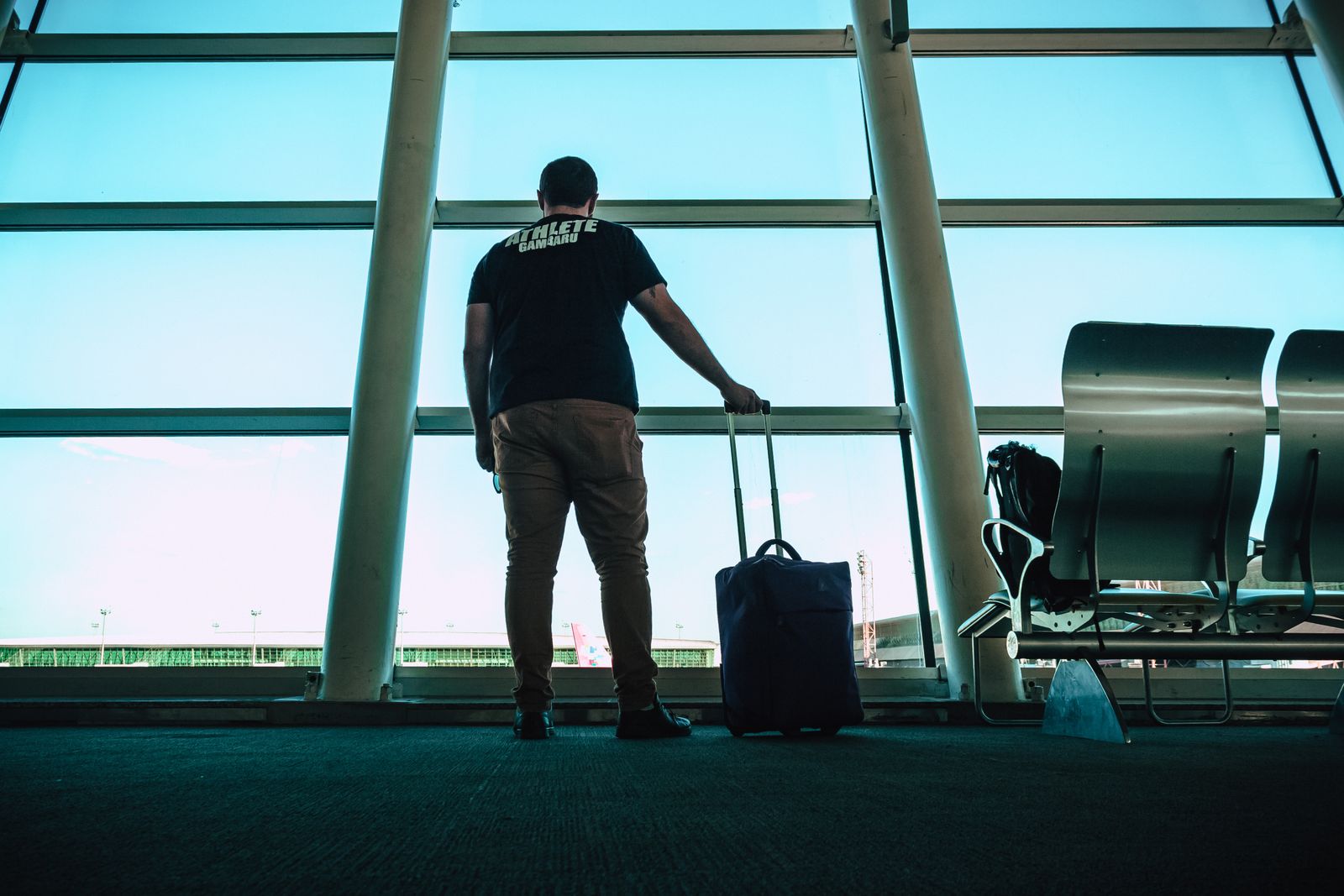 A traveller with a suitcase at an airport window