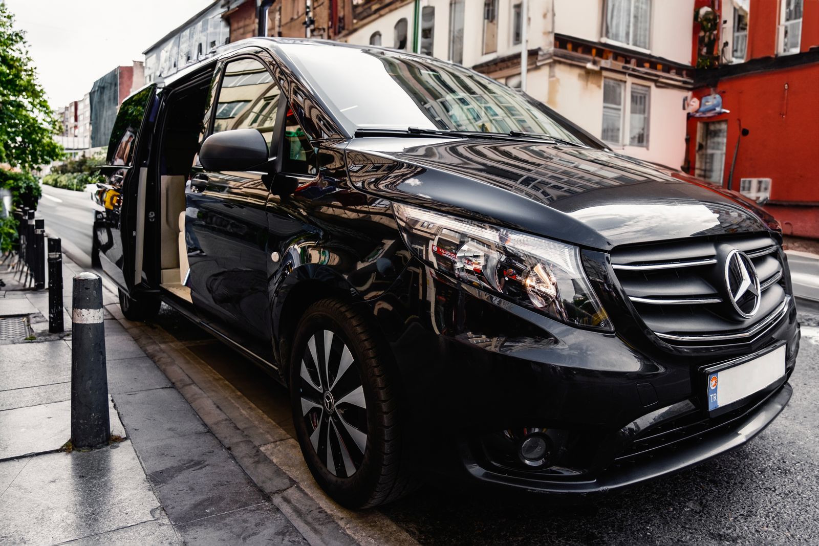 A black passenger van with the side door open on a city street